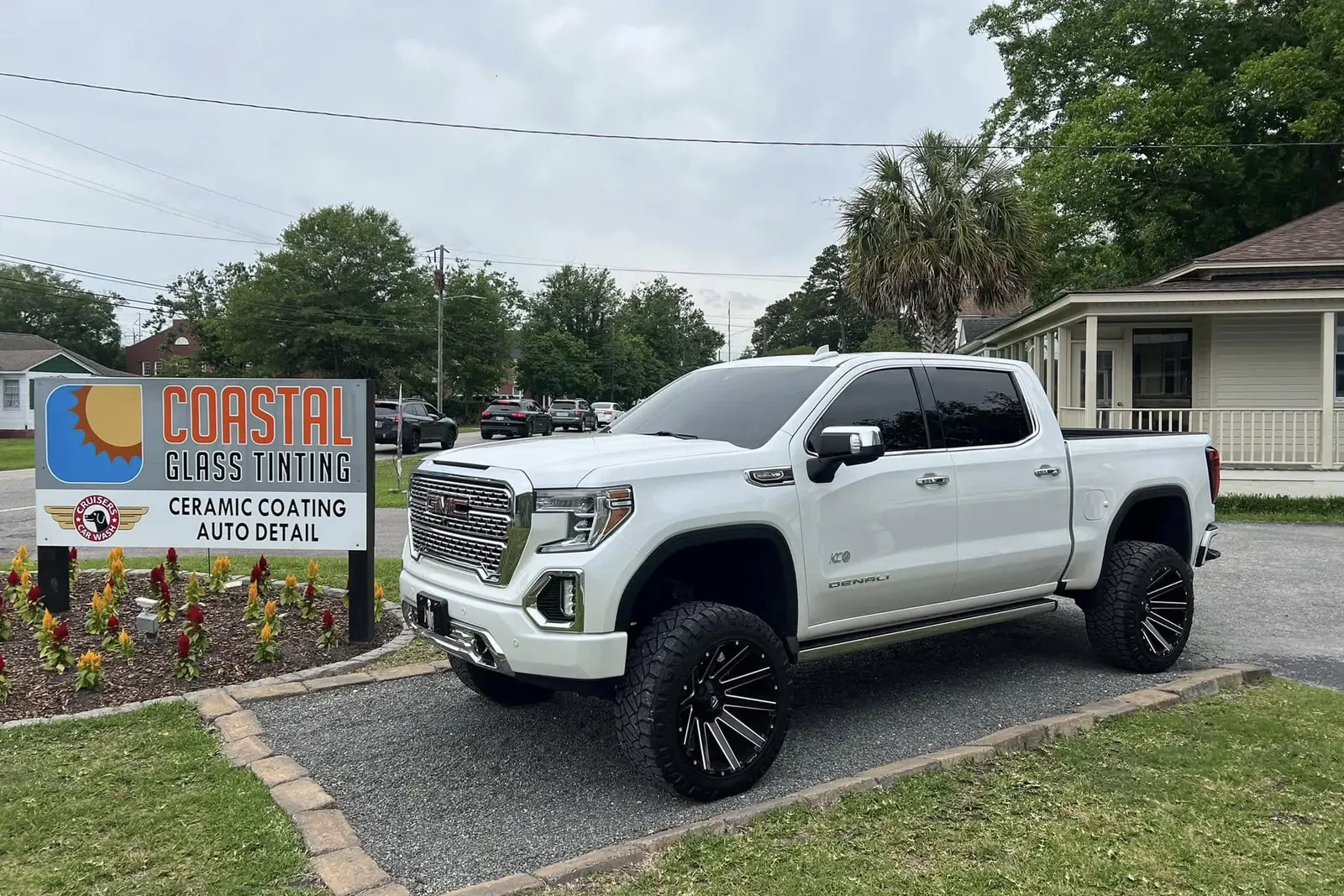 White GMC pickup with tinted windows beside the Coastal Glass Tinting sign