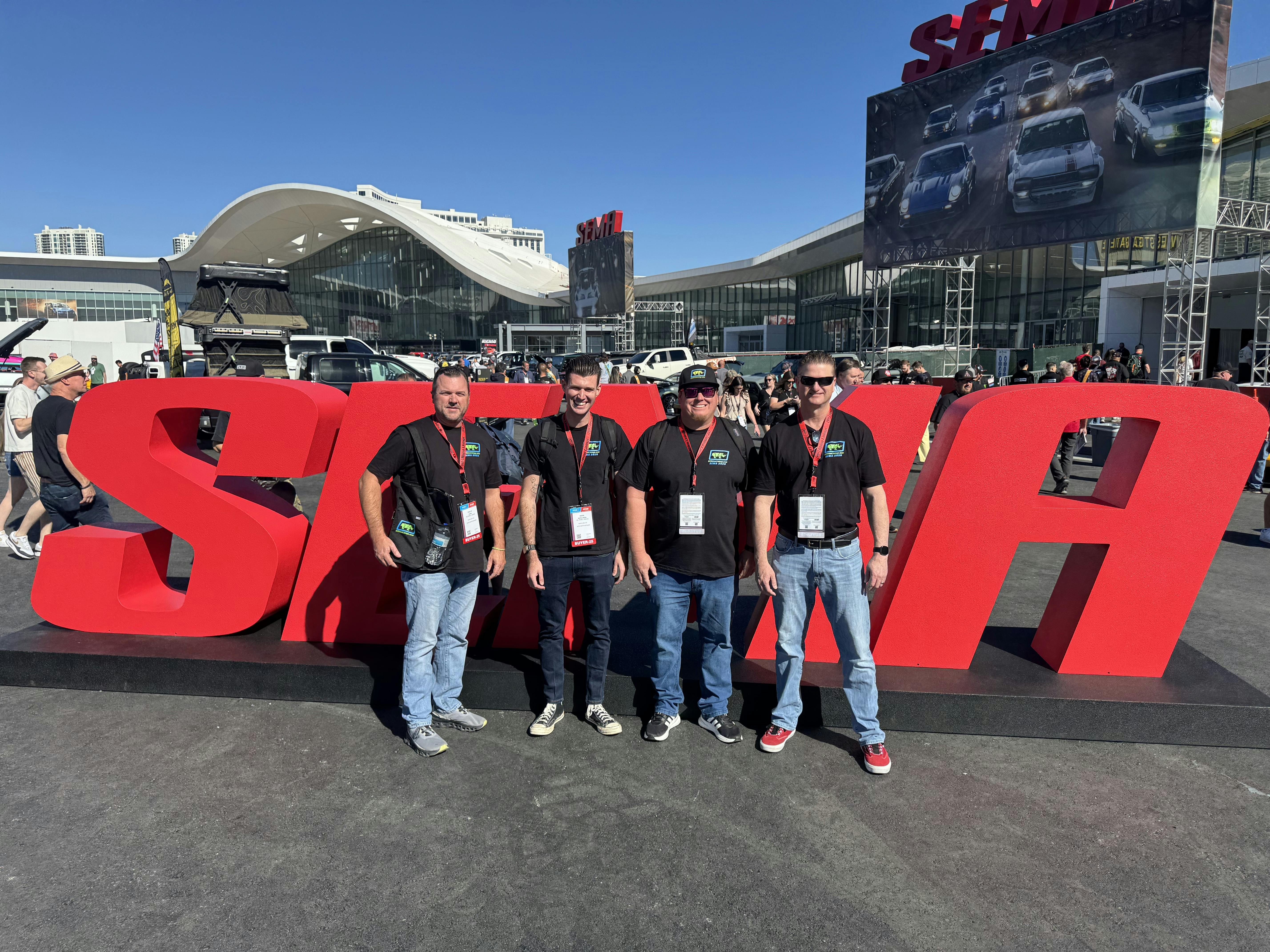 A group of men posing for a photo in front of a large red signAI-generated content may be incorrect.