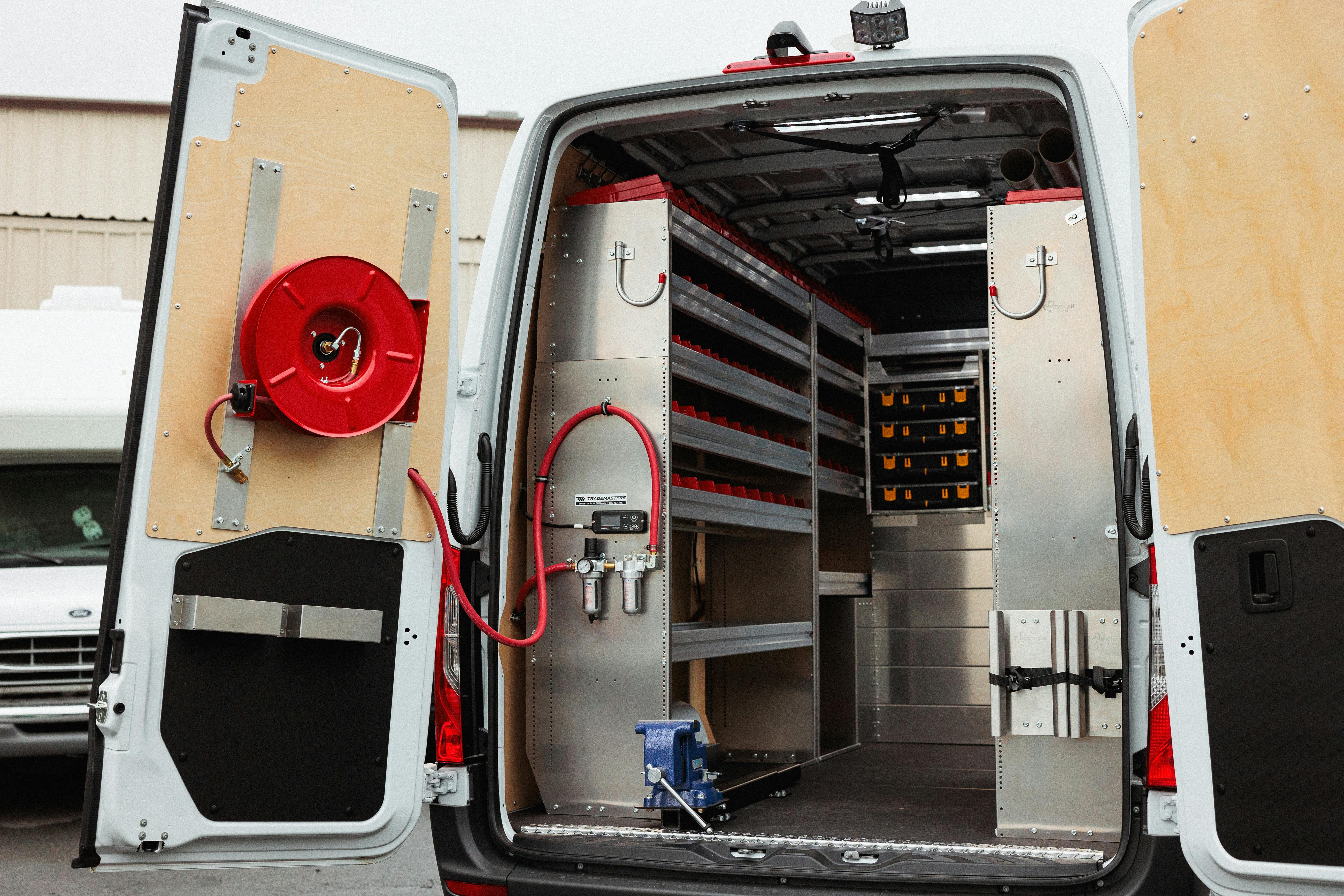 Commercial service van upfit with shelving, drawers, tool storage, and hose reel